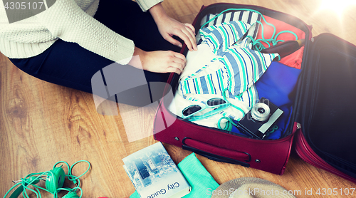 Image of close up of woman packing travel bag for vacation