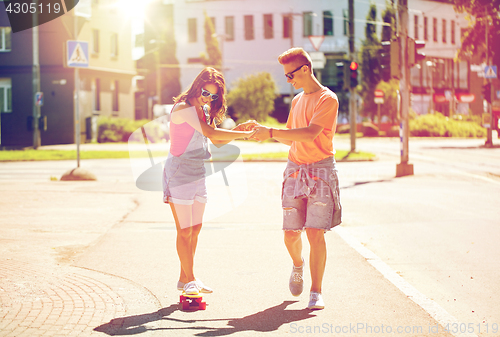 Image of teenage couple riding skateboards on city street