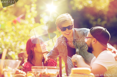 Image of happy friends having dinner at summer garden party