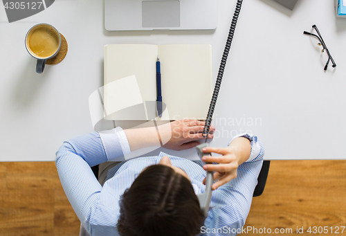 Image of businesswoman calling on phone at office table