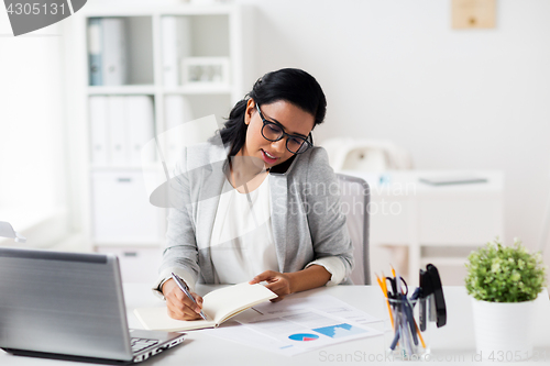 Image of businesswoman calling on smartphone at office