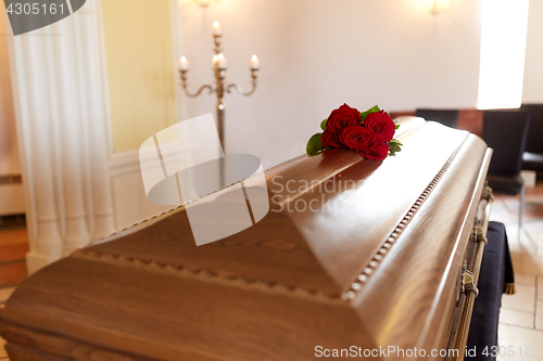 Image of red rose flowers on wooden coffin in church