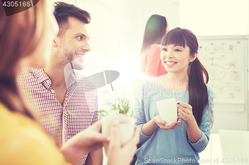 Image of happy creative team drinking coffee at office