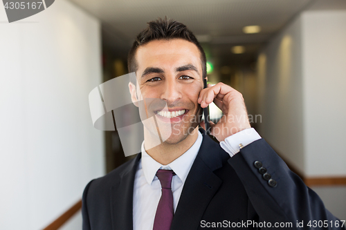 Image of smiling businessman calling on smartphone at hotel