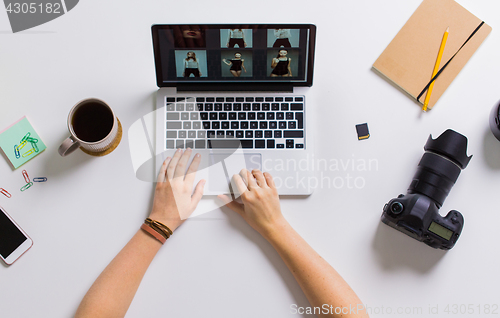 Image of woman hands with camera working on laptop at table