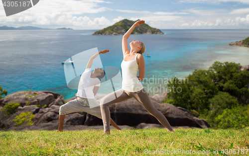 Image of couple doing yoga over natural background and sea