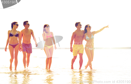 Image of smiling friends in sunglasses on summer beach