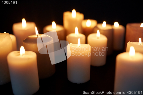 Image of candles burning in darkness over black background