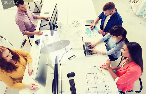 Image of creative team with computers, blueprint at office