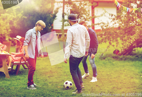 Image of happy friends playing football at summer garden