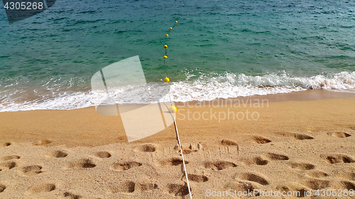 Image of Rope with floats and footprints on sandy beach