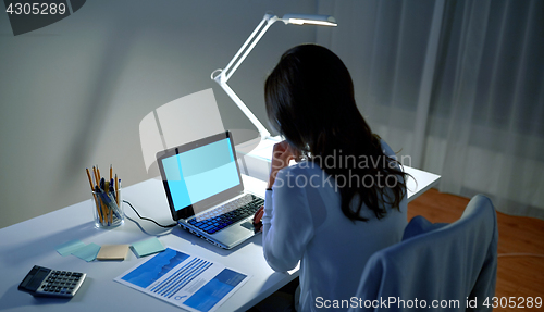 Image of businesswoman with laptop at night office