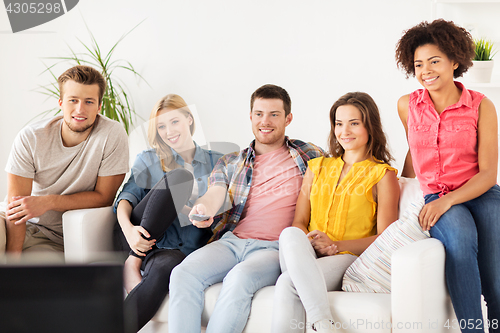 Image of happy friends with remote watching tv at home