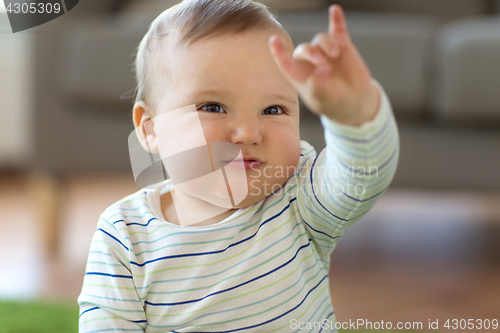 Image of baby boy showing rock hand sign at home