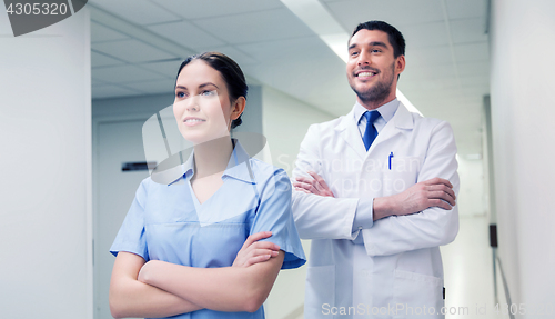 Image of smiling doctor in white coat and nurse at hospital