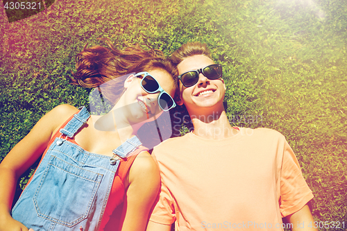 Image of happy teenage couple lying on grass at summer