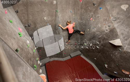 Image of young woman exercising at indoor climbing gym wall