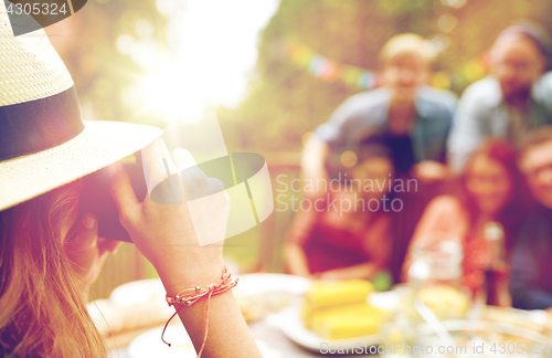 Image of woman photographing friends at summer garden party