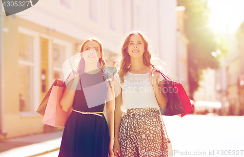 Image of happy women with shopping bags walking in city 