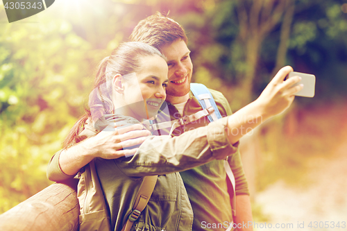 Image of couple with backpacks taking selfie by smartphone