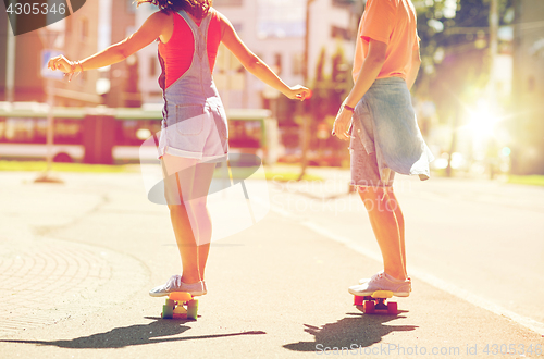 Image of teenage couple riding skateboards on city street