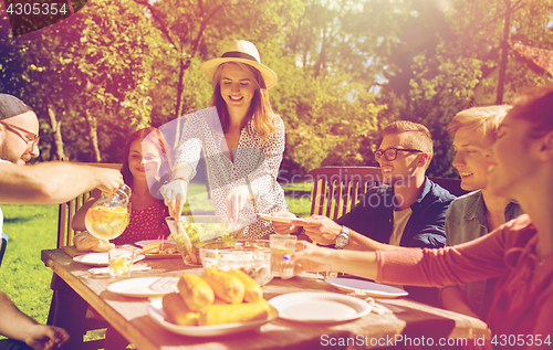 Image of happy friends having dinner at summer garden party