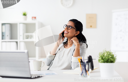 Image of businesswoman calling on smartphone at office