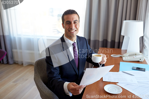 Image of businessman with papers drinking coffee at hotel