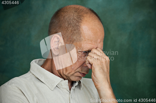 Image of Worried mature man touching his head.