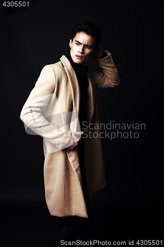 Image of cool real young man in coat on black background