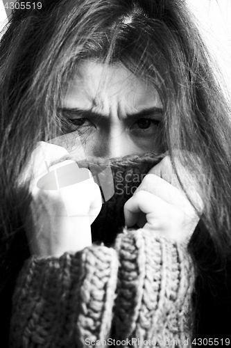 Image of young brunette gloomy woman in sweater all over her face, messed hair