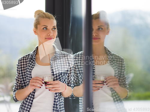 Image of young woman drinking morning coffee by the window