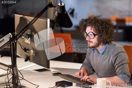 Image of man working on computer in dark startup office