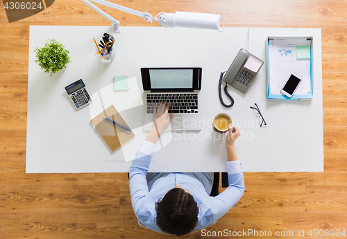 Image of businesswoman with laptop and coffee at office