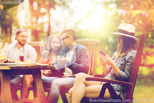 Image of woman with smartphone and friends at summer party