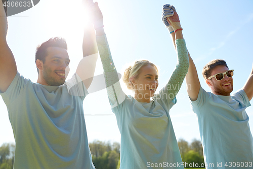 Image of group of happy volunteers holding hands outdoors