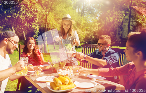 Image of happy friends having dinner at summer garden party