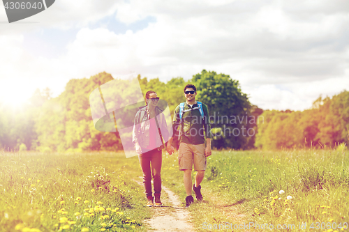 Image of happy couple with backpacks hiking outdoors