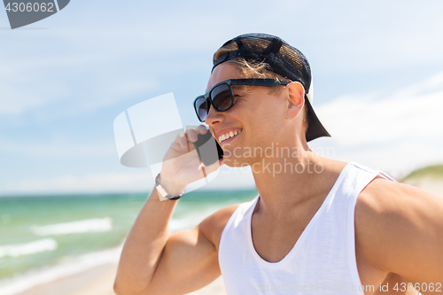 Image of smiling man calling on smartphone on summer beach