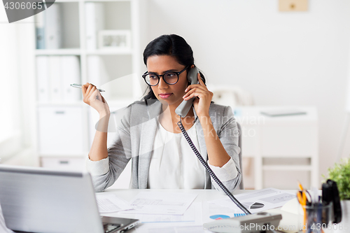 Image of businesswoman calling on phone at office