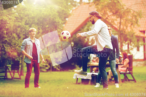 Image of happy friends playing football at summer garden