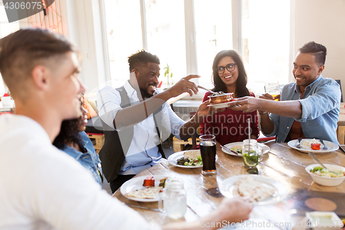 Image of happy friends eating at restaurant