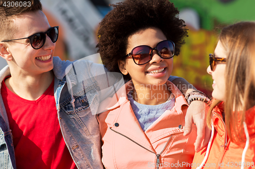 Image of happy teenage friends in shades talking on street