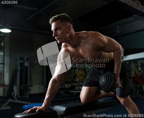 Image of man with dumbbell and bench exercising in gym