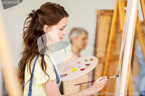 Image of student girl with easel painting at art school