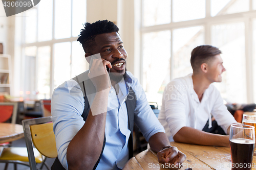 Image of man calling on smartphone and drinking beer at bar