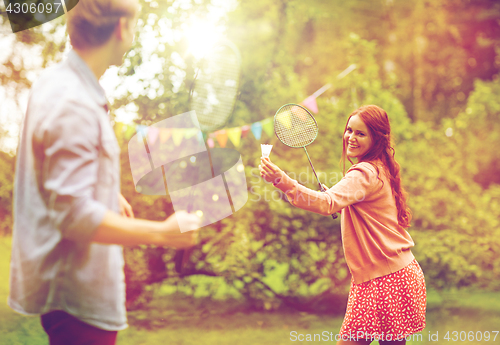 Image of happy friends playing badminton at summer garden