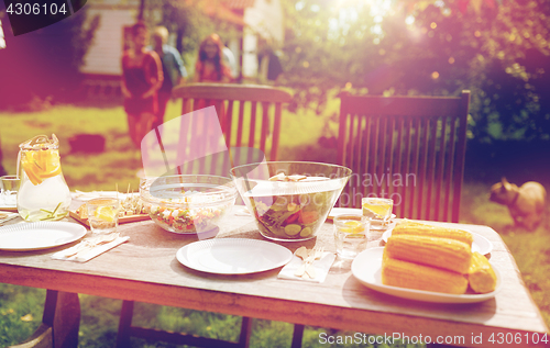 Image of people coming to table with food at summer garden