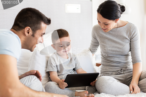 Image of happy family with tablet pc in bed at home