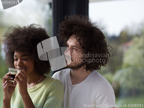 Image of happy multiethnic couple relaxing at modern home indoors